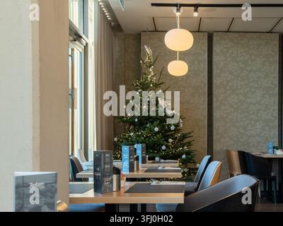Szklarska Poreba, Poland - December 18, 2025: A Radisson dining area setup with a decorated pine tree creating a cozy seasonal holiday atmosphere in a Stock Photo
