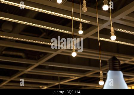 Hanging White LED Light Bulbs on Cords from Industrial Grey Ceiling Beams in Loft Stock Photo