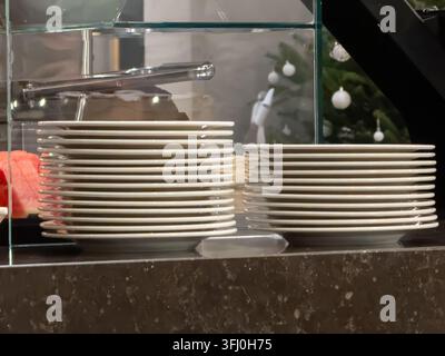 Clean ceramic dishes piled in rows on a sleek surface during festive catering service, highlighting efficient organization and preparation for hospita Stock Photo