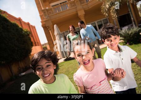 Happy modern Middle Eastern Arab family with smiling children playing together in a sunny backyard villa Stock Photo