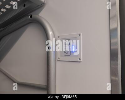 An electronic audio interface with glowing level lights for volume management mounted on a clean white surface to improve accessibility for passengers Stock Photo