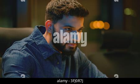 Concentrated serious Arabian business man working with laptop at evening office Indian guy overworked looking in monitor Hindu businessman male agent Stock Photo