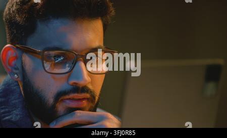 Thinking Indian business man in glasses looking at graph digital tablet reflection in eyeglasses Arabian businessman talk look at trading result Stock Photo