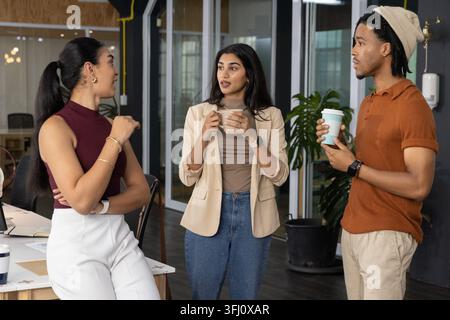 Team chatting in office left woman gesturing launching animated timeline on laptop for marketing. Breakroom, openplan, colleagues, discussion, collabo Stock Photo