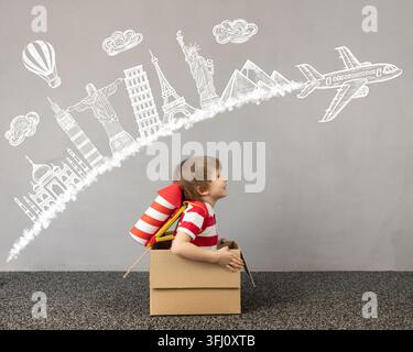 Child playing at home. Kid sitting in cardboard box. Child dreaming about travel. Children imagination and travel concept Stock Photo