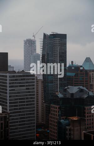 Aerial view of the modern skyscrapers and high-rise buildings in the city skyline with a construction crane under an overcast sky in Vancouver, Britis Stock Photo