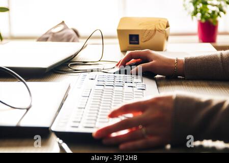 Close-up of hands typing on a keyboard and using a mouse at a wooden desk in a bright office setting. Warm backlighting, professional atmosphere, idea Stock Photo