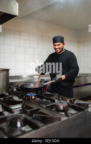 Happy chef cooking food in Pan at industrial kitchen Stock Photo