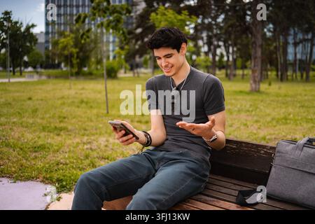 Young adult man smiling using smartphone in park Stock Photo