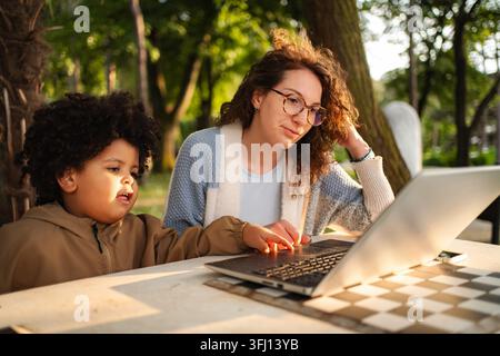Mother and child using laptop for remote learning outdoors Stock Photo