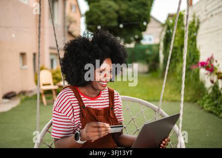 Black woman online shopping using credit card on laptop Stock Photo