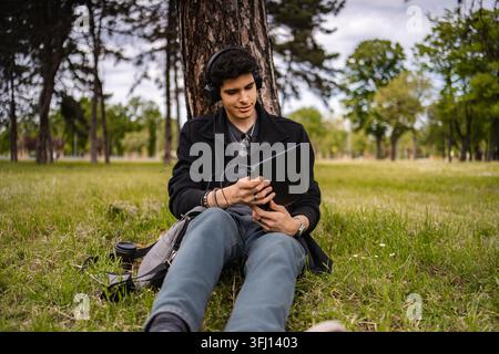 Young adult man listening to music and using digital tablet outdoors Stock Photo
