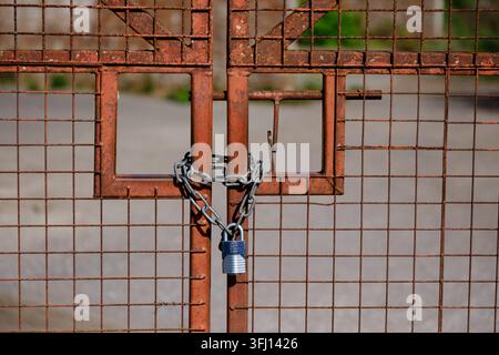 Close up of heavy duty gate closed with big chain and padlock attached for security. Stock Photo