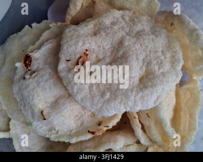 Close-up pile of Indonesian traditional rice crackers, known as kerupuk puli or papadam, showcasing crisp textured surfaces and spices Stock Photo