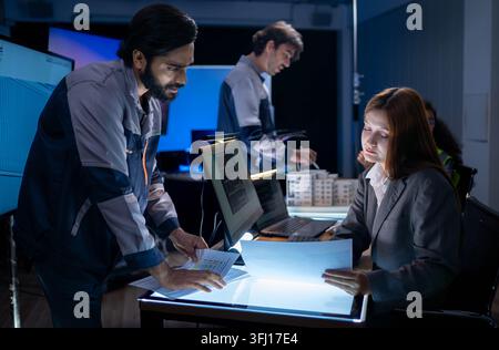 Engineering professionals reviewing architectural plans and digital project documents during collaborative technology development meeting in modern of Stock Photo