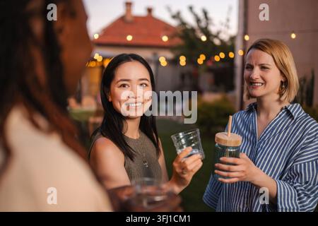 Multi-ethnic friends enjoying backyard party on summer evening Stock Photo