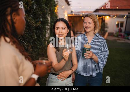 Multi ethnic women friends enjoying backyard party conversation Stock Photo