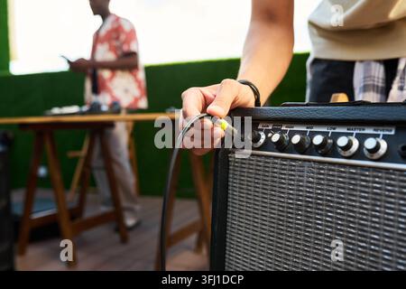 Man Plugging Cable into Guitar Amplifier at Outdoor Event Stock Photo