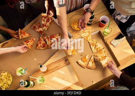 Diverse Group of Friends Sharing Pizza at Outdoor Party Stock Photo