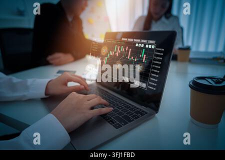 A business professional focuses on a laptop displaying complex financial data and AI-driven analytics in a modern office setting. Colleagues are blurr Stock Photo