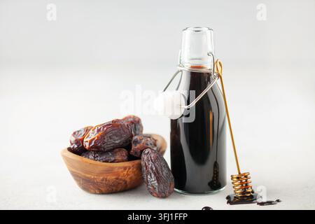Natural dates syrup in bottle with whole dates in white background. Eco natural sweetener. Sweet healthy sauce for porridge and Stock Photo