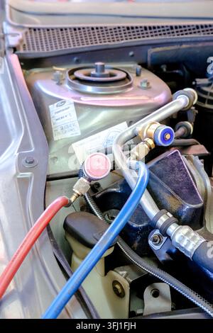 Automotive technician connecting hoses to car ac system for refrigerant service Stock Photo