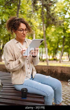 Woman using a tablet in green park remote working Stock Photo