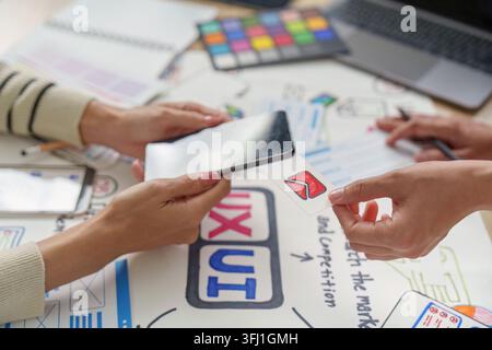 Two women designers collaborate on mobile app UI UX, using a transparent phone overlay to visualize augmented reality prototypes with an email icon Stock Photo