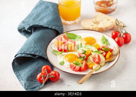 Healthy breakfast. Fried eggs and vegetables - cherry tomatoes, avocado slices, spinach leaves, sweet pepper and parsley in plat Stock Photo