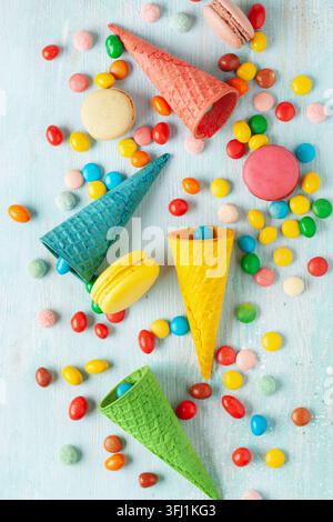 Different colorful candies, lollipops, marshmallows and macaroons in candy cane. Flat lay sweets on light background. Top view Stock Photo