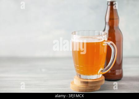 Beer is poured from dark brown bottle into beer glass. Stock Photo