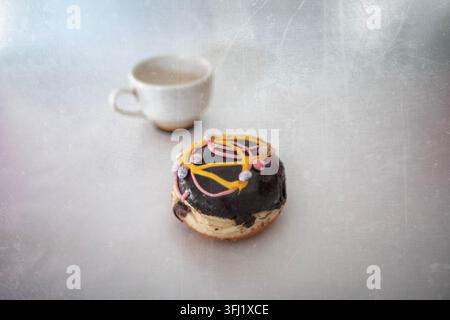 Vintage photo of a decorative chocolate donut and a mug of green tea Stock Photo