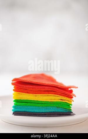 Rainbow Cake Crepe on white plate. Rainbow as symbol of inclusivity, LGBT pride. Stock Photo