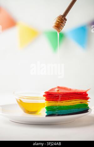 Rainbow Cake Crepe on white plate. Rainbow as symbol of inclusivity, LGBT pride. Stock Photo