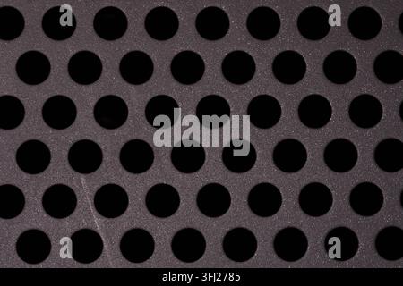 Geometric pattern of evenly spaced circular openings in a perforated metal sheet. Clean industrial texture suitable for design, engineering and techno Stock Photo