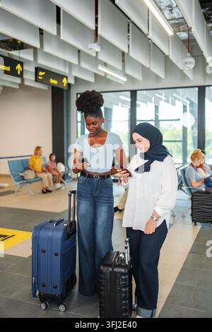 Diverse friends checking smartphones preparing for airport travel Stock Photo