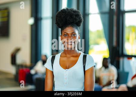 Young adult Black woman traveling through an airport smiling Stock Photo