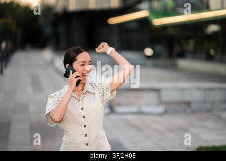 Happy woman celebrating success while talking on smartphone Stock Photo