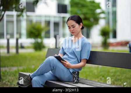 Female medical professional using digital tablet on bench Stock Photo