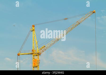 Yellow Construction Tower Crane Against a Blue Summer Sky Stock Photo