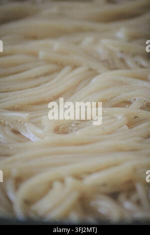 Close up of spaghetti boiling in water with bubbles and foam during the cooking process Stock Photo