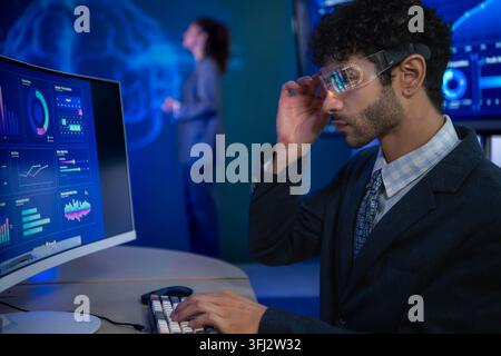 Business executive wearing smart glasses analyzing digital dashboards and business intelligence metrics in a modern office, demonstrating AI powered a Stock Photo