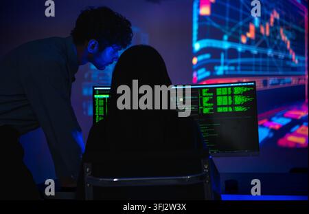 Software engineers collaborating on cybersecurity monitoring and AI powered code analysis in a modern technology workspace with multiple digital displ Stock Photo