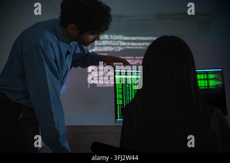 Software engineers collaborating on cybersecurity monitoring and AI powered code analysis in a modern technology workspace with multiple digital displ Stock Photo
