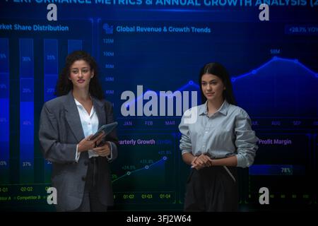 Business professionals analyzing performance metrics and annual growth trends using interactive financial dashboards during a strategy meeting Stock Photo