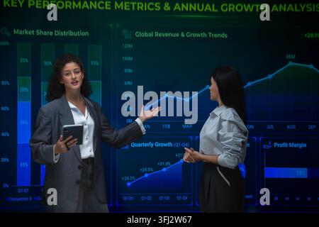 Business professionals analyzing performance metrics and annual growth trends using interactive financial dashboards during a strategy meeting Stock Photo