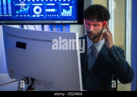 Business executive wearing smart glasses analyzing digital dashboards and business intelligence metrics in a modern office, demonstrating AI powered a Stock Photo