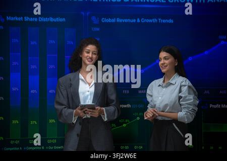 Business professionals analyzing performance metrics and annual growth trends using interactive financial dashboards during a strategy meeting Stock Photo