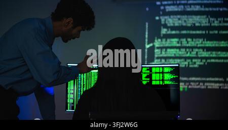 Software engineers collaborating on cybersecurity monitoring and AI powered code analysis in a modern technology workspace with multiple digital displ Stock Photo