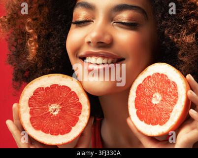 Mixed-race young woman holding grapefruit halves in a creative studio portrait Stock Photo
